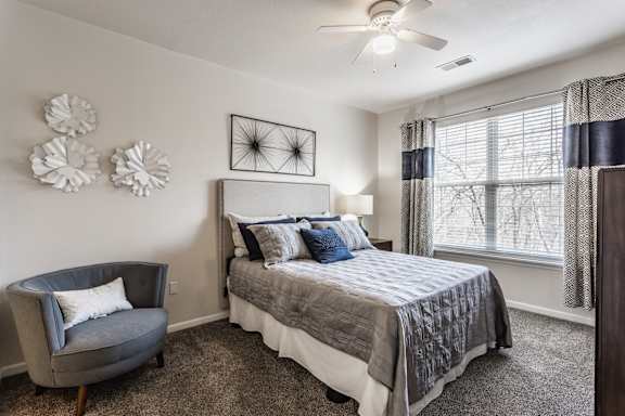 A bedroom with a bed, chair, and decorative items on the wall.