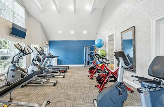 A gym with a row of stationary bikes and a mirror on the wall.