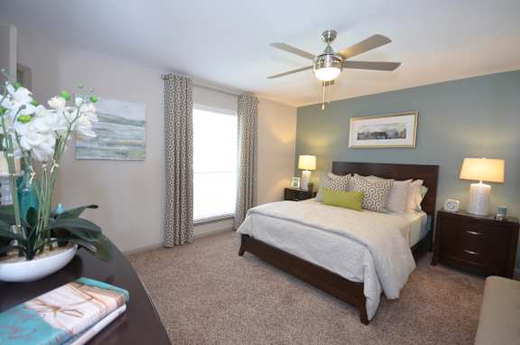 A bedroom with a bed, nightstands, and a ceiling fan.