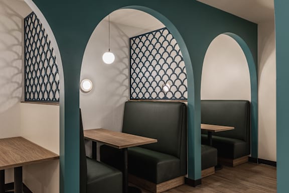 A restaurant with a green wall and black chairs.