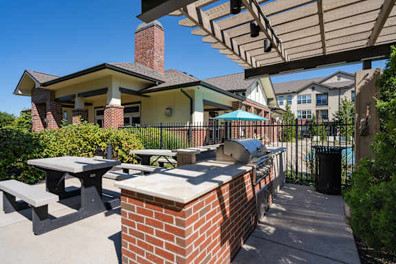 A patio with a brick chimney and a grill.