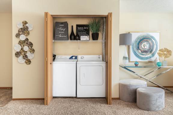 A laundry room with a washer and dryer, a glass table, and decorative items.