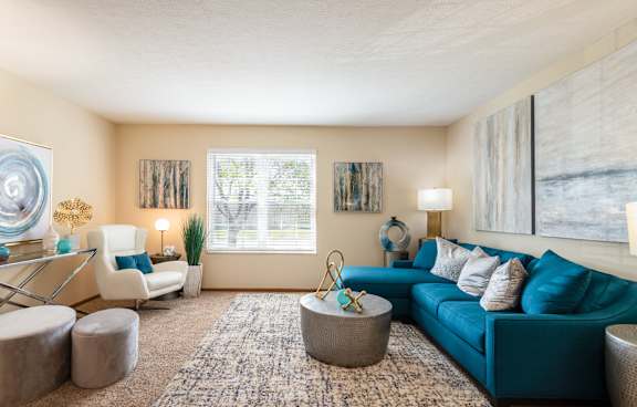 A living room with a blue couch and a rug.