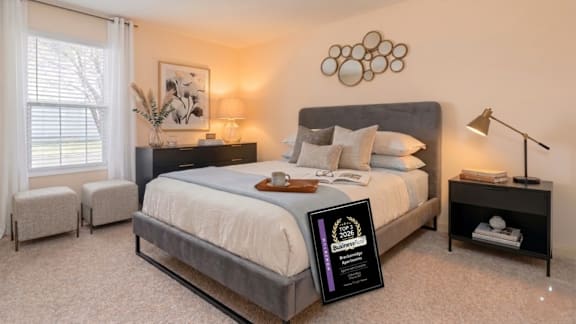 A bedroom with a large bed, a nightstand, and a window with white curtains.