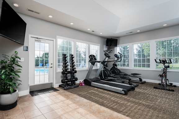 A home gym with a variety of exercise equipment including a treadmill, stationary bike, and a bench press.