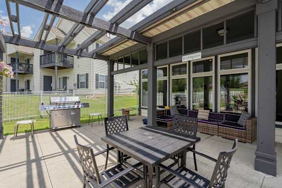 A patio with a table and chairs is covered by a roof.