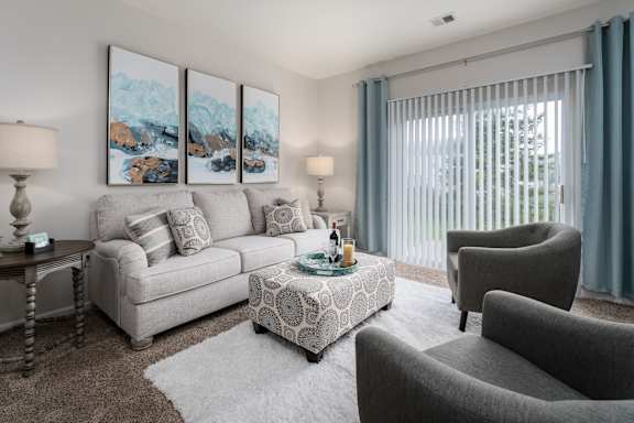 A living room with a grey couch, a coffee table, and a painting on the wall.