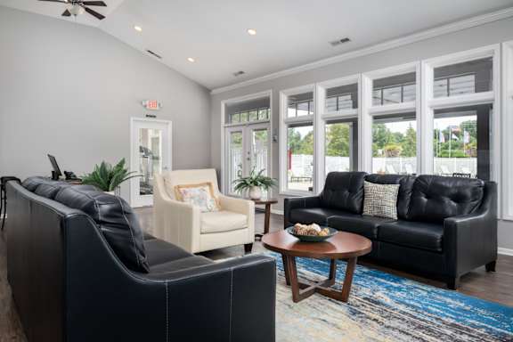 A living room with a black couch, a white chair, and a coffee table.