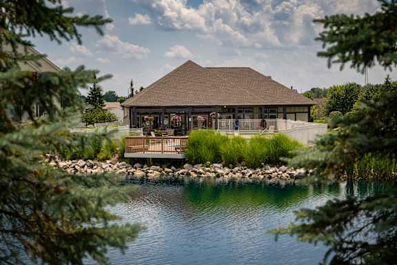 A building with a brown roof is surrounded by water and trees.