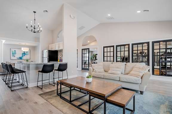 A modern living room with a bar area and a large window.