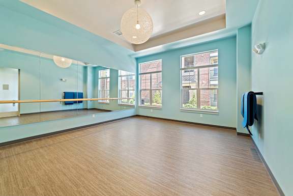 A spacious dance studio with wooden floors and mirrors on the walls.