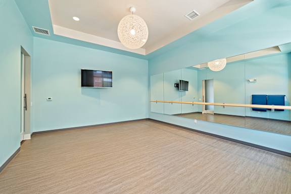 A spacious room with a ballet barre and mirrors on the wall.