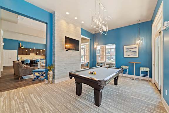 A pool table is in the middle of a room with blue walls.