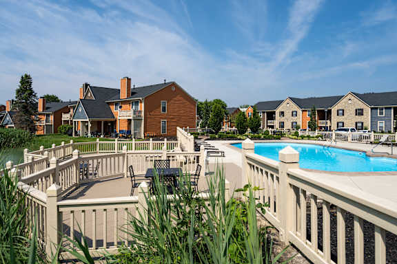 A pool surrounded by a white fence with a building in the background.