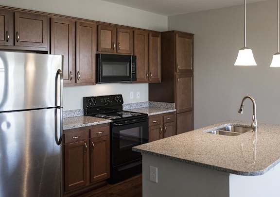 A kitchen with brown cabinets and a stainless steel refrigerator.