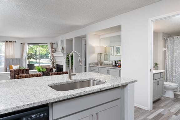 A modern kitchen with a marble countertop and a view of the backyard.