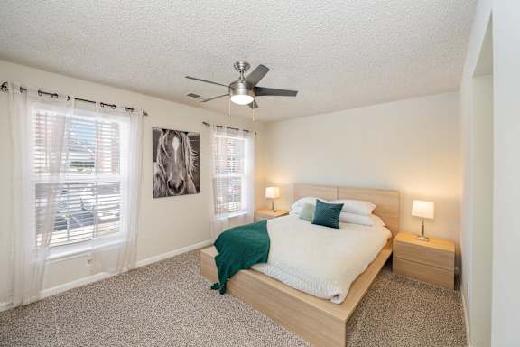 A bedroom with a bed, nightstands, and a ceiling fan.