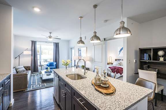 A kitchen with a granite countertop and pendant lights.