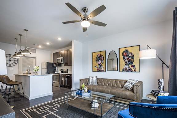 A living room with a brown couch and a ceiling fan.