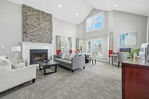 A living room with a stone fireplace and grey couches.