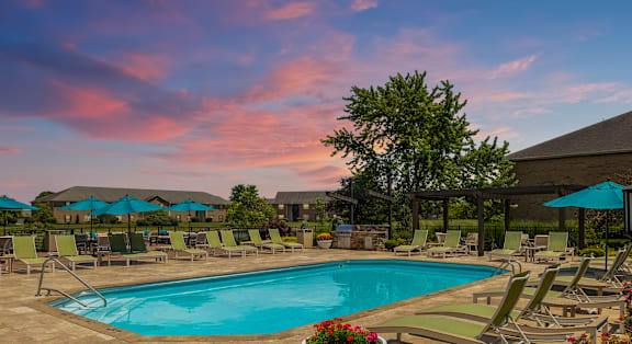 a resort style pool with lounge chairs and umbrellas