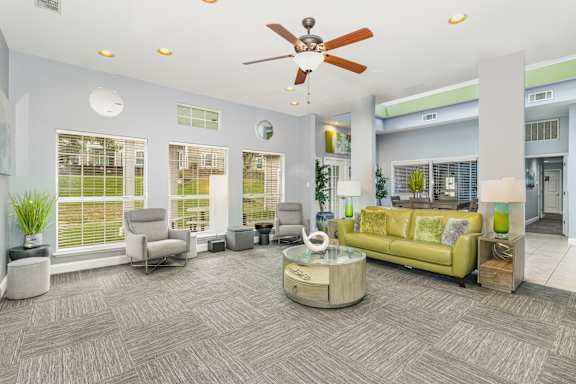 A living room with a green couch and a ceiling fan.