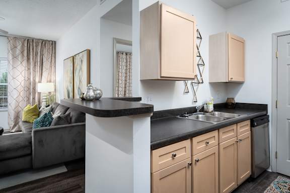 A kitchen with a black countertop and beige cabinets.