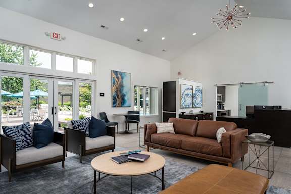 A living room with a brown couch, a coffee table, and a large window.