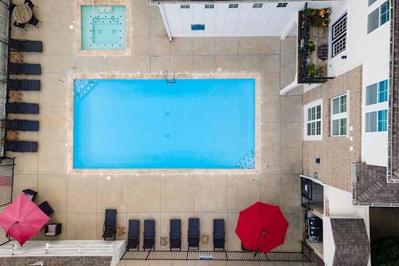 A large swimming pool surrounded by lounge chairs and umbrellas.