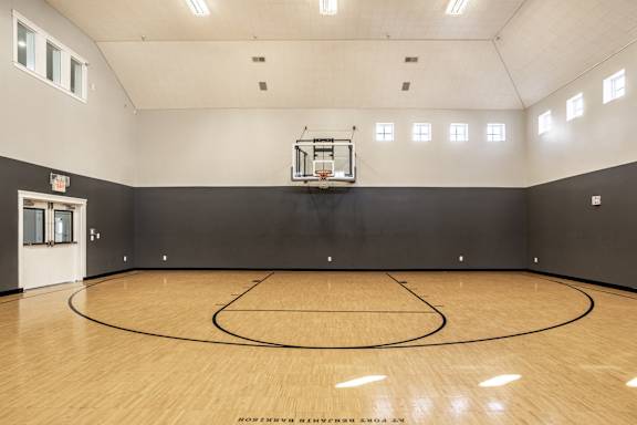 A basketball court with a wooden floor and a basketball hoop.