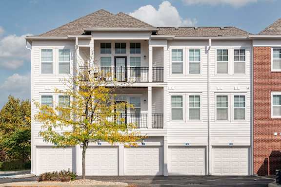 A white two story apartment building with a tree in front.