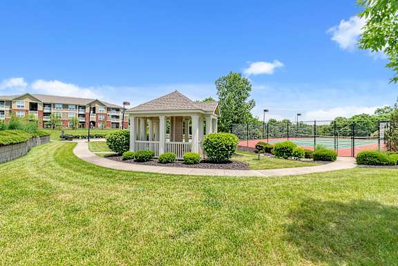 A gazebo is surrounded by a grassy area and apartment buildings.