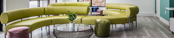 A green sofa with a glass table in front of it.