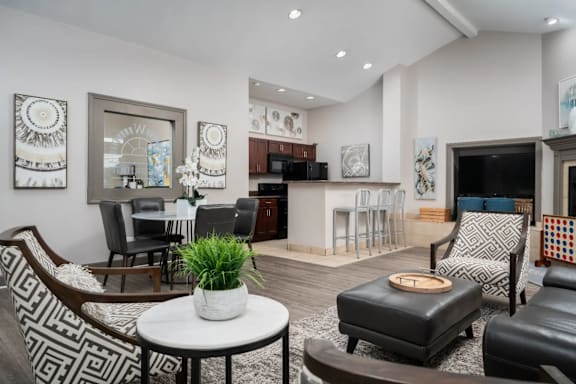 A living room with a black and white patterned chair and a white table with a plant on it.
