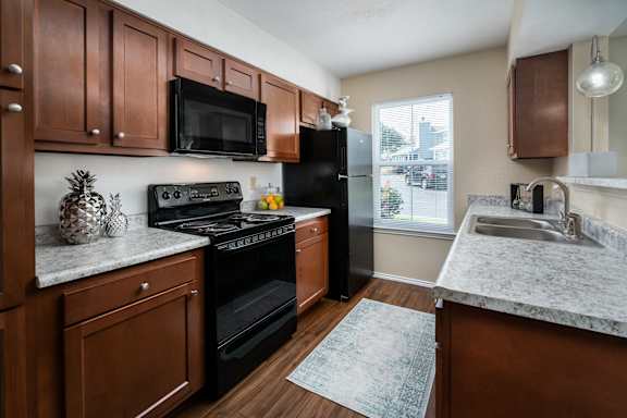 A kitchen with brown cabinets and a black oven.