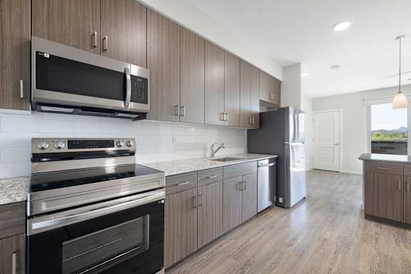 A modern kitchen with dark wood cabinets and stainless steel appliances.