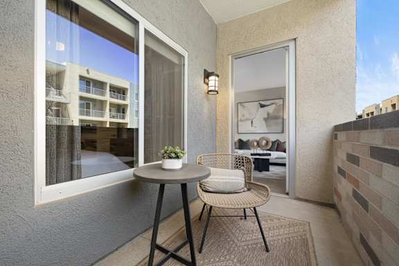 A balcony with a table and chairs overlooking a building.