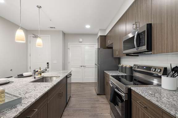 A modern kitchen with dark wood cabinets and stainless steel appliances.