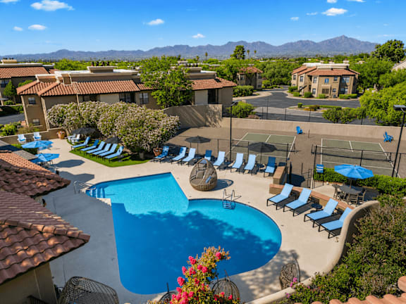 A pool surrounded by lounge chairs and umbrellas.