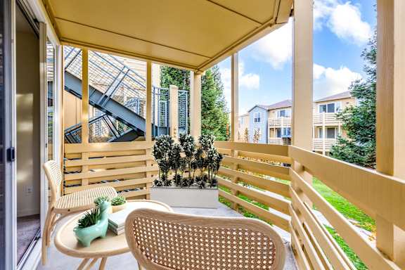 A patio with a chair and a table with a vase on it.