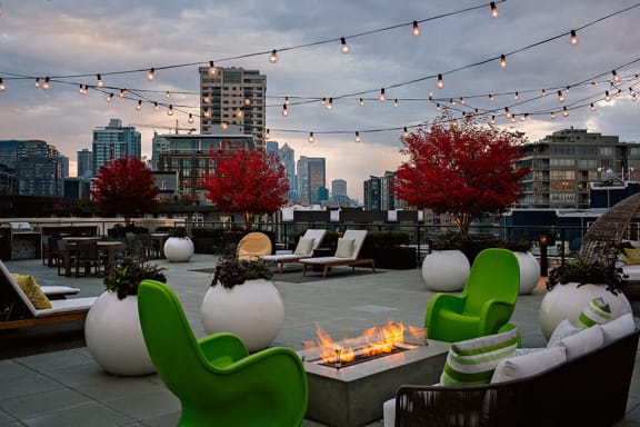 a rooftop lounge with a fire pit and a view of the city