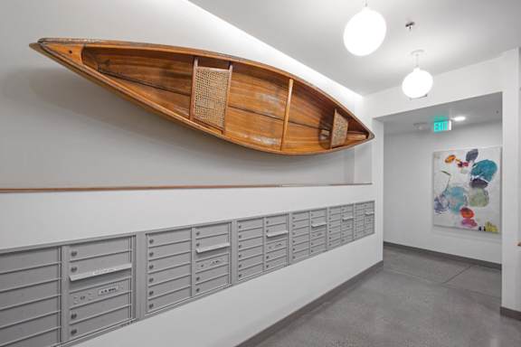 A wooden boat mounted on a wall above a row of mailboxes.