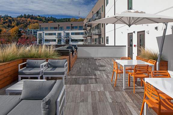 A patio with a white table and chairs and a grey couch.