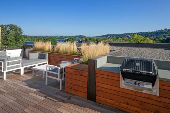 A patio with a grill and chairs overlooking a body of water.