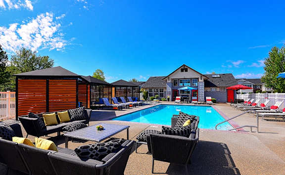 the swimming pool at our apartments with chairs and tables