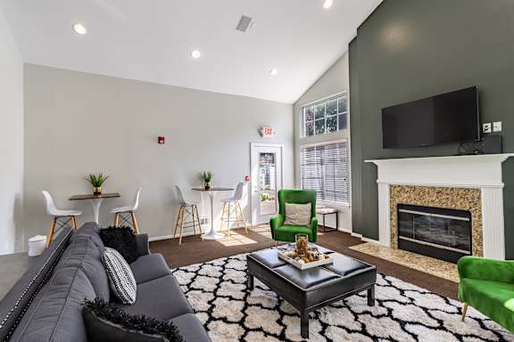 A living room with a grey couch, a black coffee table, a green armchair, and a fireplace.