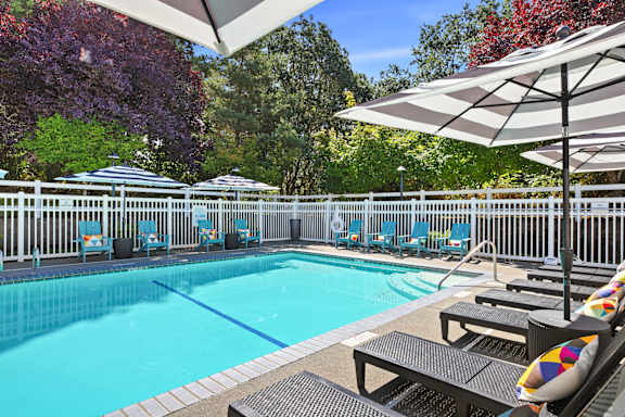 A pool surrounded by trees and chairs.