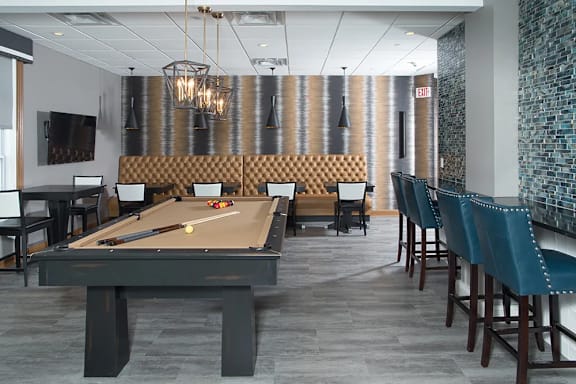 A pool table is in the middle of a room with chairs around it.