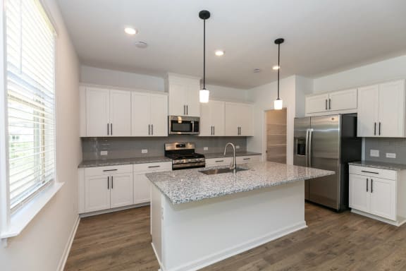 a kitchen with white cabinets and a marble counter top