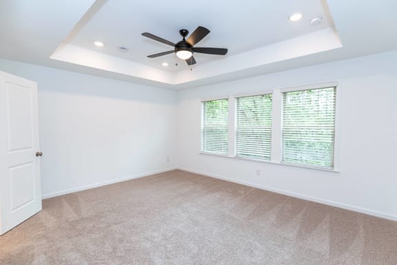 an empty living room with a ceiling fan and a window